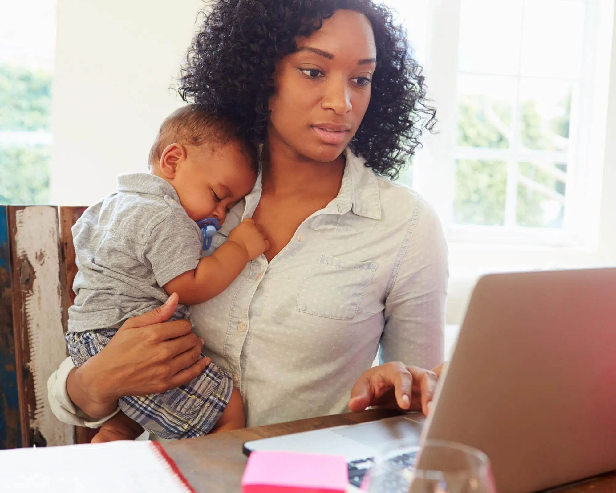 Mother working at home with baby reading email from theatre company