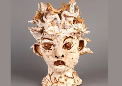 This is an image of a sculpture of a bust with a bird's nest from clay and colored slips by a head, made by artist Amy Nolan.