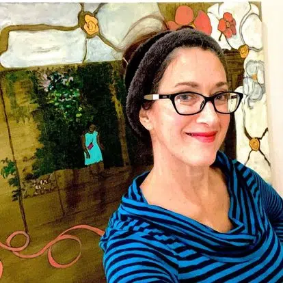 Artist, Elena Allee, with her paintings in the background.